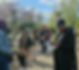 Group walking in a sunny park, some reading leaflets.