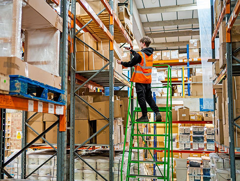Warehouse worker scanning inventory from a ladder