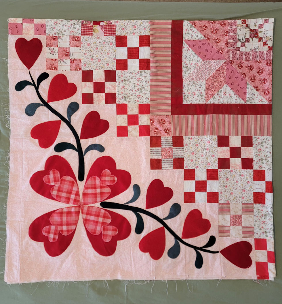 Pink and red heart-themed patchwork quilt with floral and checkered blocks, black vine, on a green background
