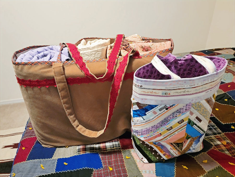 Two fabric bags on a multicolored quilt; one brown with red lace trim, the other patterned with text "moda." Background is a plain wall.