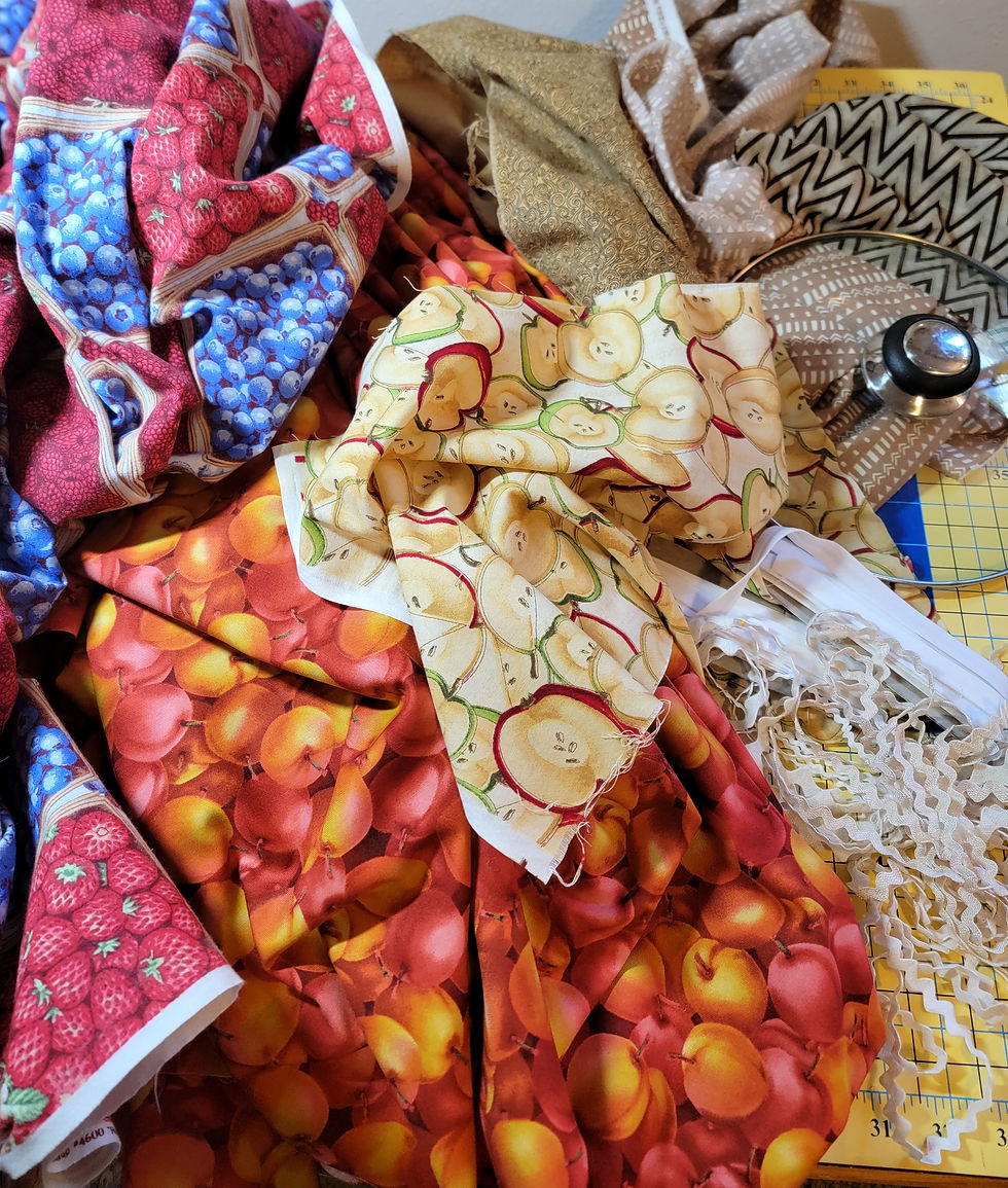 Colorful fruit-print fabric swatches and trim spread on a cutting mat, with a rotary cutter on the right.