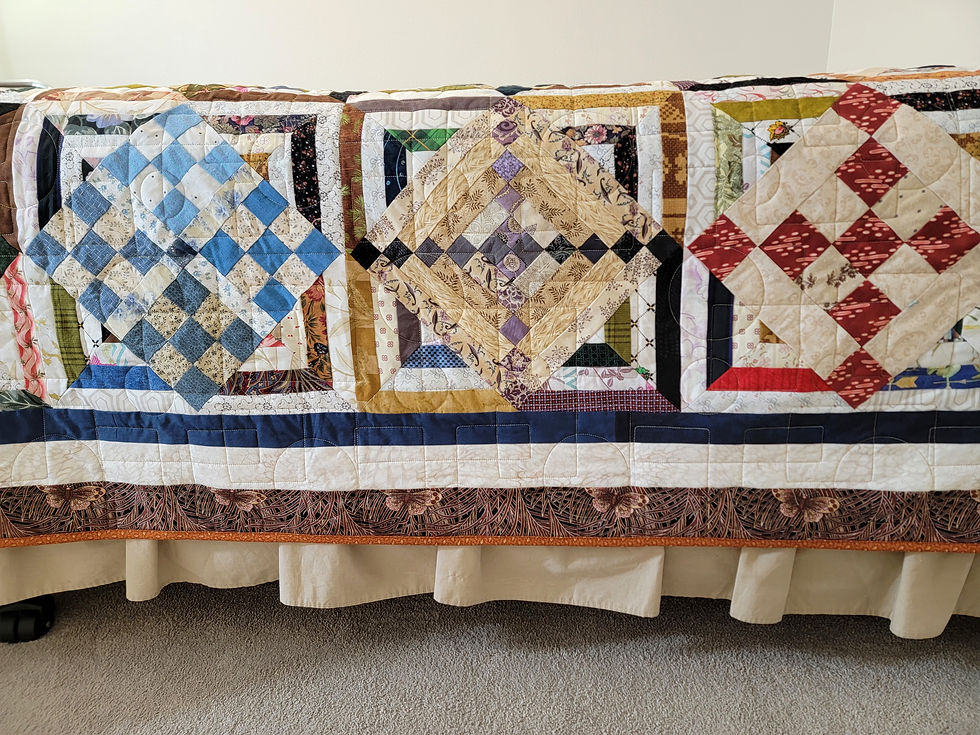 Patchwork quilt with blue, gold and red diamond blocks draped over a bed