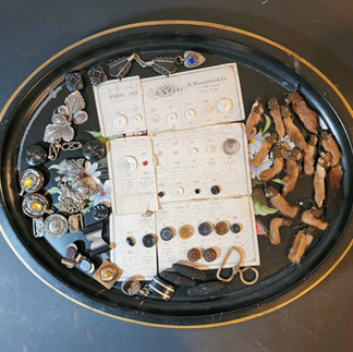 A black floral tray filled with an assortment of buttons