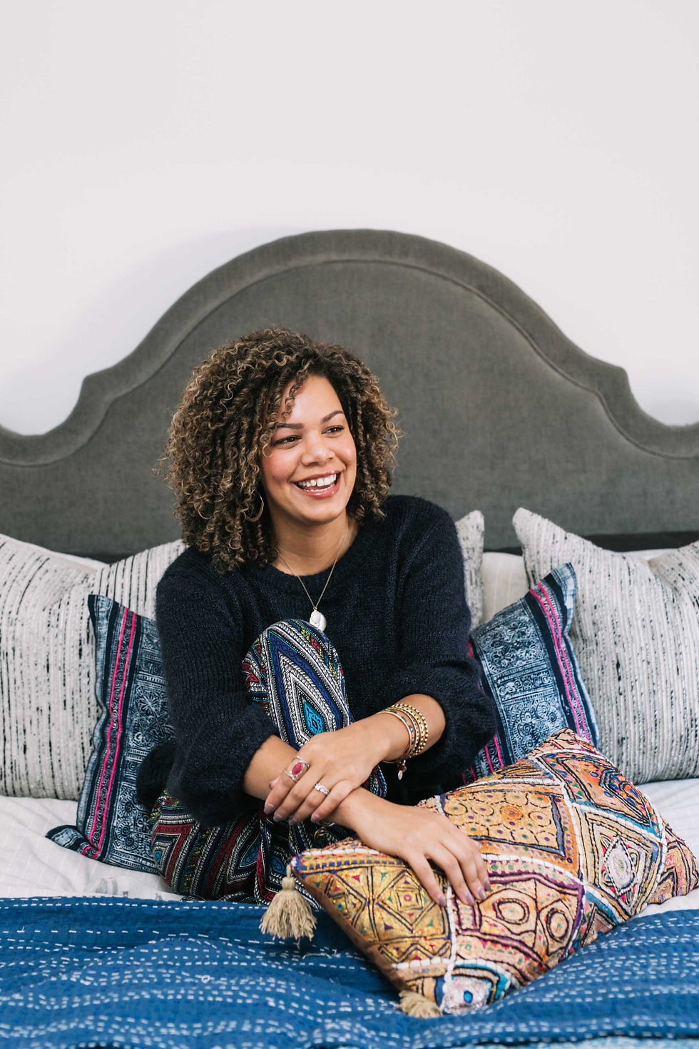 Laura Thurman smiling in a beautifully styled bedroom showcasing Thurman Design Studio's interior design aesthetic.