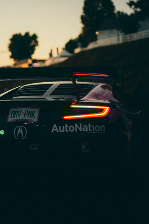 Rear view of black Acura NSX GT3 Evo number 86 with AutoNation sponsorship and illuminated taillights in paddock at 2019 Petit Le Mans