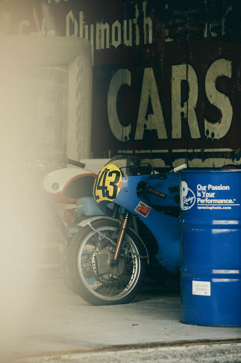 Blue 1960s Pops Yoshimura Honda CB race bike number 43 with yellow racing number in garage with oil drums in LaPlace Louisiana