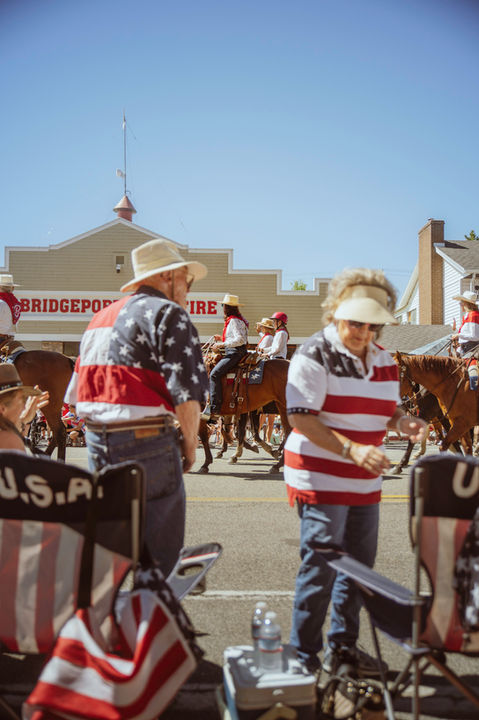 People in American flag clothing participating in 4th of July parade with horses and riders in Bridgeport California
