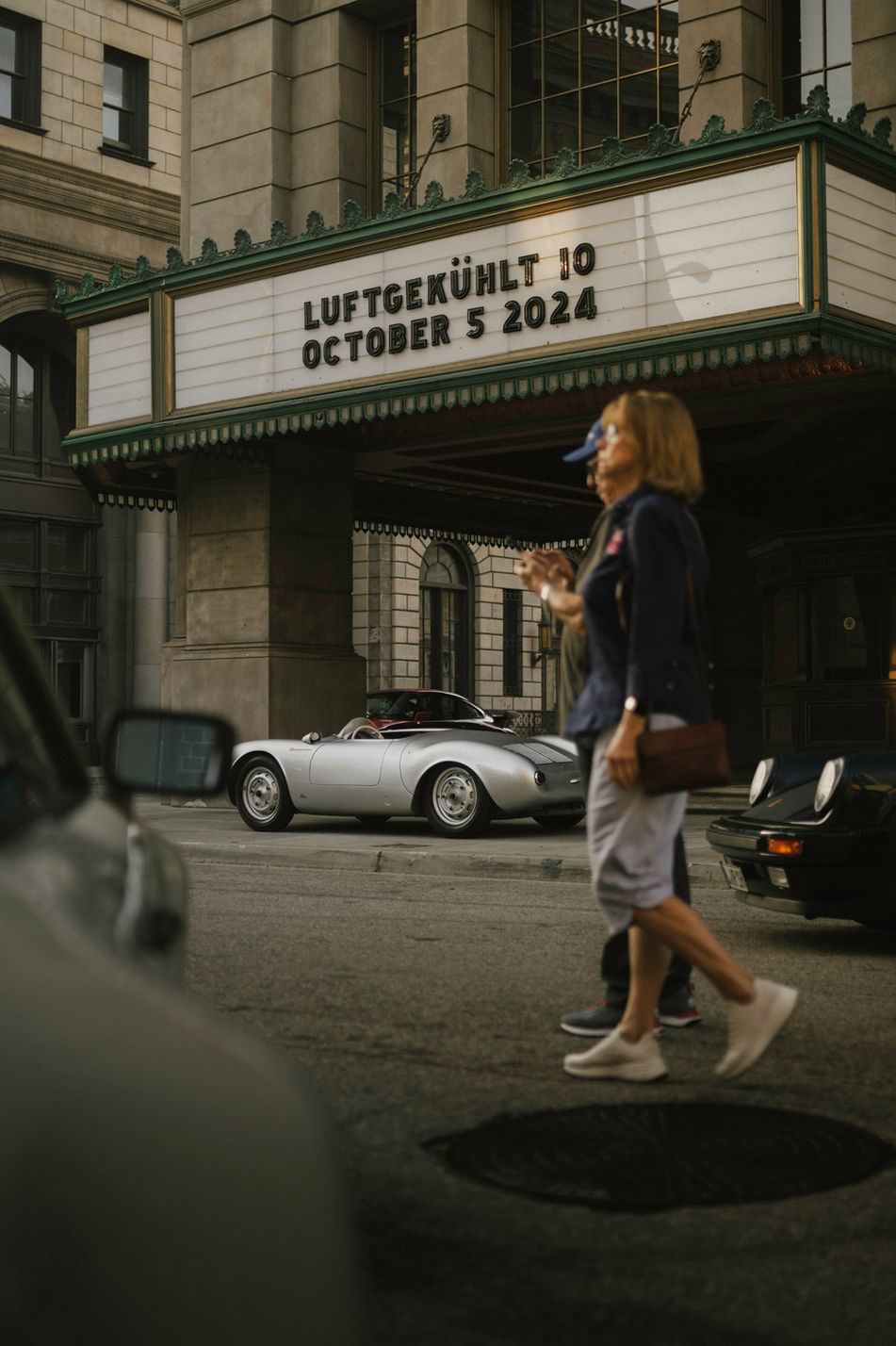Silver Porsche 550 Spyder parked in front of historic theater with Luftgekühlt 10 October 5 2024 marquee at Universal Studios Los Angeles