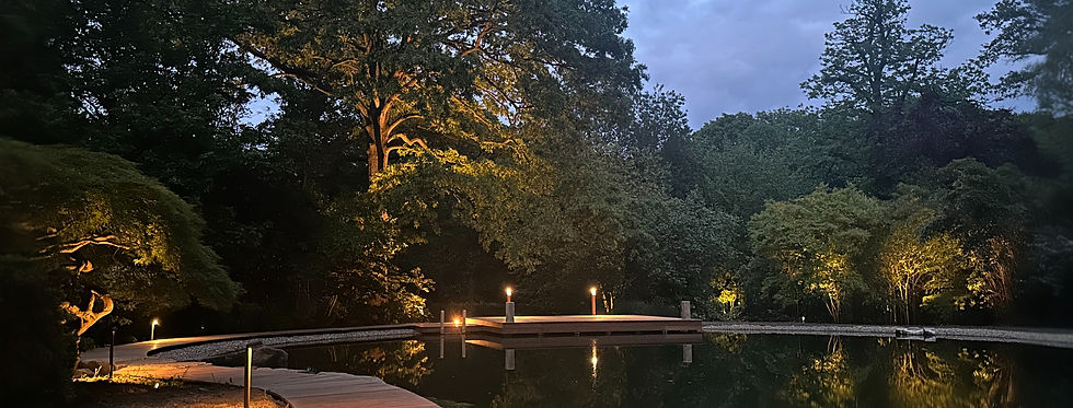uplit trees and boardwalk lighting around a private lake
