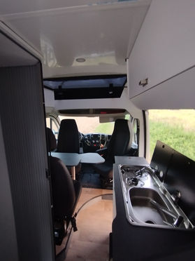 Ein moderner Campervan. Der Van ist weiß mit schwarzen Akzenten und bietet Platz für mehrere Personen, ideal für Camping und Roadtrips.
