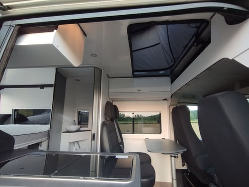 Ein moderner Campervan. Der Van ist weiß mit schwarzen Akzenten und bietet Platz für mehrere Personen, ideal für Camping und Roadtrips.