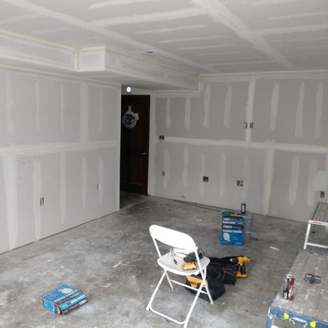 Interior drywall installation in a room, with tools and a folding chair. Drywall installed by Quality Coat LLC.