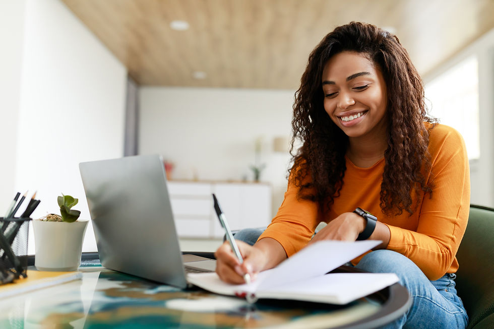Happy young woman taking notes in front of computer