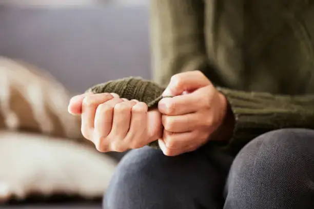"Image depicting a person clenching their long sleeves tightly in one hand while pinching the fabric with the other, symbolizing the challenges of anxiety.
