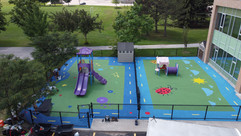 Drone shot of connecting green rubber playgrounds with blue tracks and colourful shapes and designs