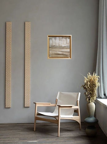 Dans un intérieur sobre et minimaliste aux tons naturels, le tableau 'Grimoire' est élégamment accroché au mur. Encadré dans un cadre en bois clair, l'œuvre abstraite aux nuances neutres et texturées attire le regard. Il est mis en valeur par un environnement épuré composé de meubles en bois clair et d'une chaise en tissu crème, créant une atmosphère sereine. À côté, une composition florale séchée apporte une touche organique, tandis que la lumière douce filtrée par un rideau léger contribue à une ambiance apaisante et harmonieuse.