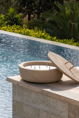 a candle with a wooden lid sits next to a pool