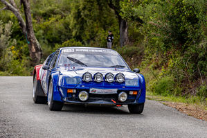 a blue alpine renault car is driving down a road