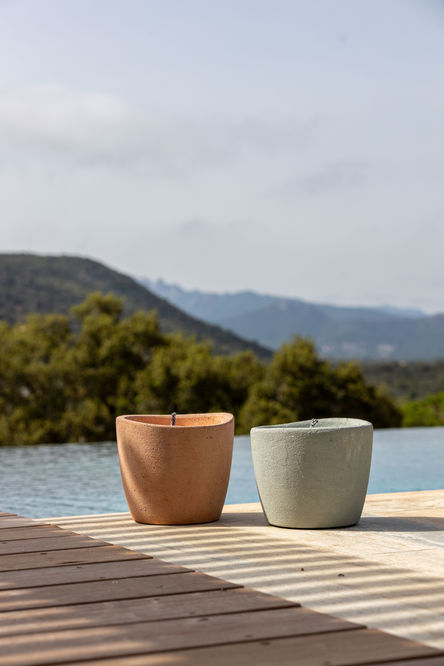 two pots are sitting on a ledge overlooking a pool with mountains in the background