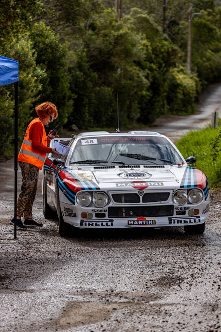 a woman stands next to a martini race car
