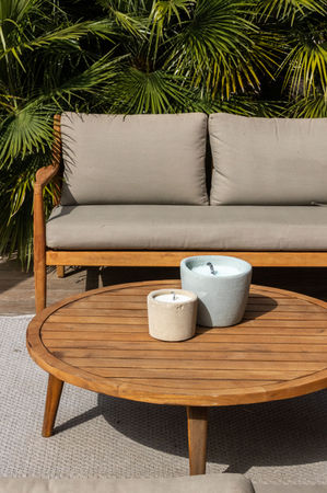 two candles sit on a wooden table in front of a couch