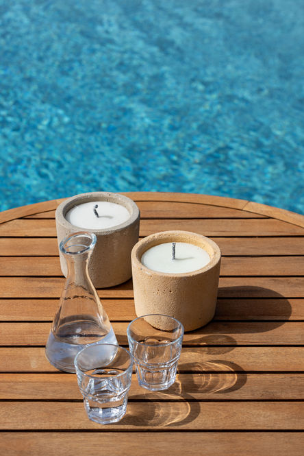two candles sit on a wooden table next to a glass of water