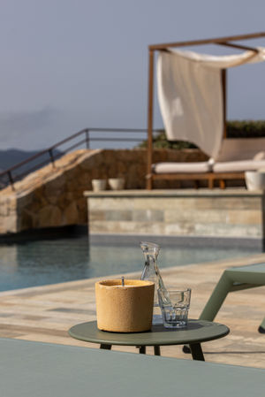 a candle and a glass sit on a table near a pool