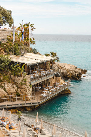 a restaurant on a cliff overlooking the ocean with tables and chairs