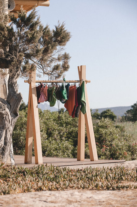 clothes hanging on a wooden rack with a tree in the background
