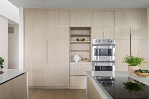 Custom wall of integrated light oak kitchen cabinets with double ovens, hidden refrigerator, and open display shelving modern kitchen design in Faver Drive Remodel