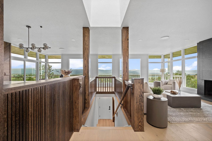 Wooden staircase with vertical slat columns and skylight, linking the kitchen and living spaces at Faver Drive Remodel.