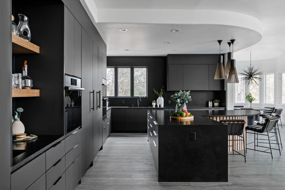 Full kitchen view with black cabinetry, sculptural pendant lights, and walnut open shelving