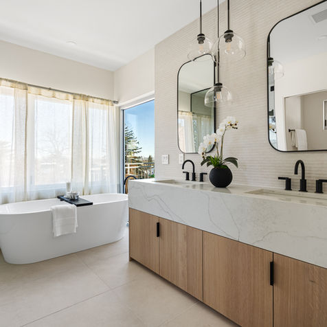 Frameless glass shower and freestanding soaking tub with mountain views in the spa-inspired primary bathroom at 2206 Alpine Drive.