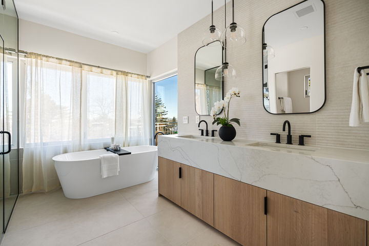 Frameless glass shower and freestanding soaking tub with mountain views in the spa-inspired primary bathroom at 2206 Alpine Drive.
