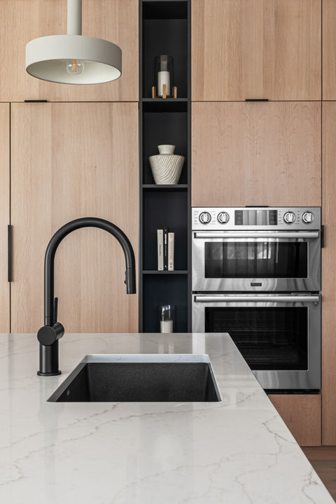 Built-in double ovens in custom oak panel cabinetry with modern black hardware at Alpine Drive home.