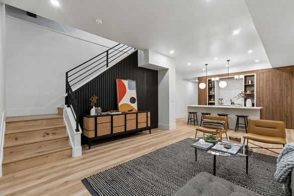 Modern basement family room with custom bar and black accent wall.