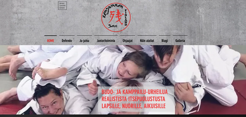 Kuva lasten ryhmästä, jossa valkoisiin budoasuihin pukeutuneet lapset ovat kasassa ohjaajan päällä