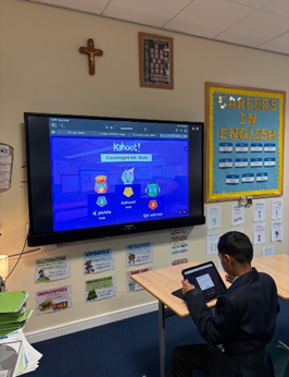 One student sat at a school desk on an iPad facing the interactive whiteboard.