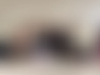 Six Girls stood linked with each other behind a long white table with various sweet treats on it as well as a purple donation bucket in the centre of the table.