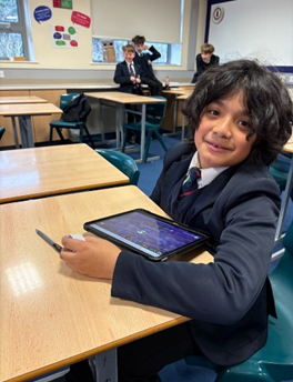 Young secondary school child sat at desk with an iPad in front of them.