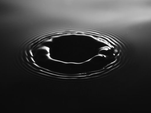 A black and white close-up of ripples spreading across dark water, like doubt spreading from a single event. 