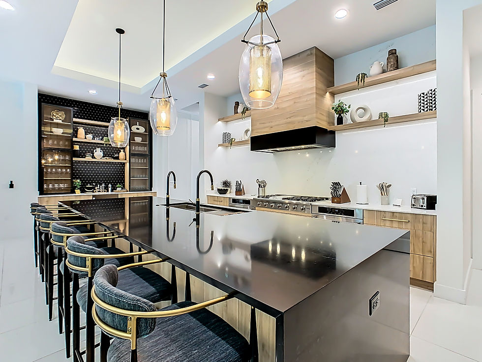Modern kitchen with glossy island, blue velvet stools, pendant lights, built-in shelves, and stainless stove in a bright, calm space