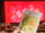 A program for The Grinch is shown in front of a blurred out view of a stage, curtain, and audience seats.