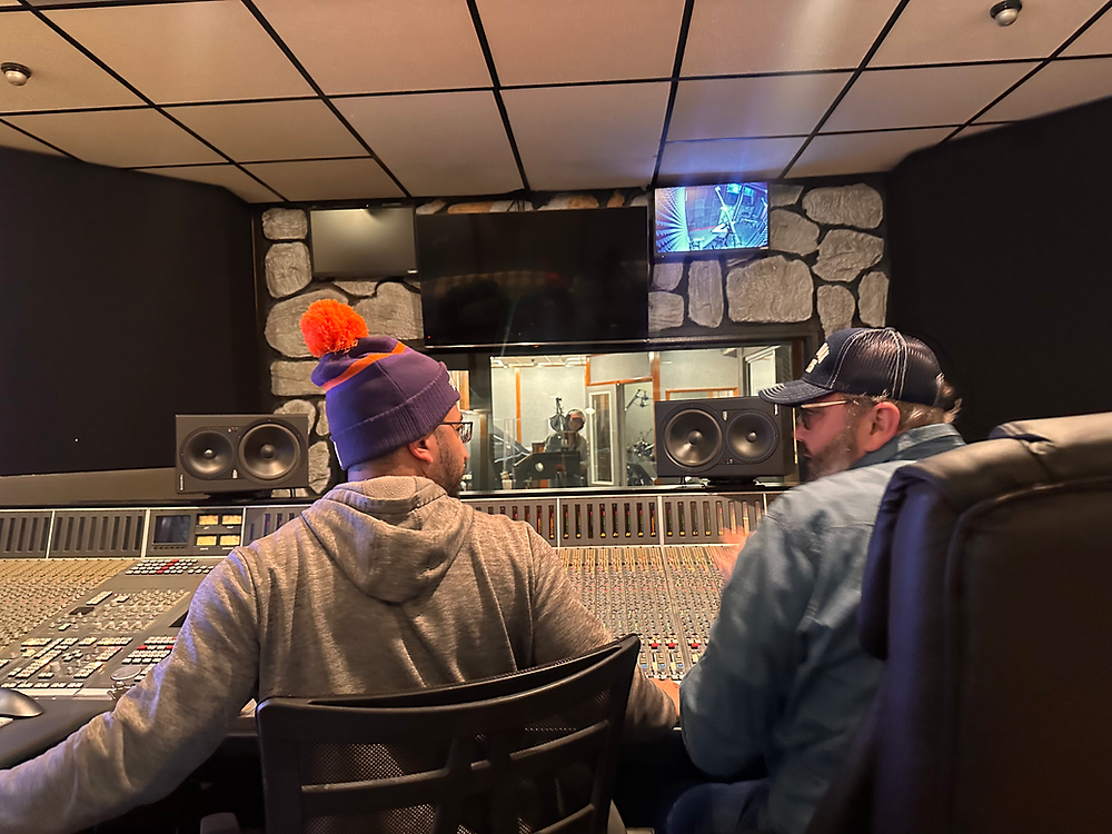 Two recording mixing engineers at a studio console.