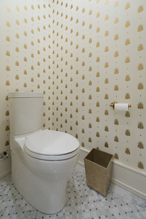 White modern toilet, tissue roll, and patterned wallpaper bathroom interior setting.