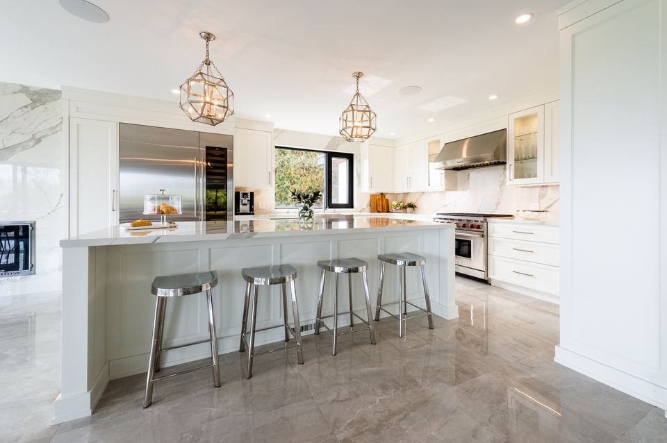 Modern white kitchen with stainless steel appliances and marble island. Julie Reinhart Design.