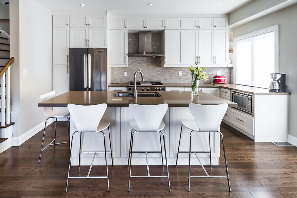 Modern kitchen with white cabinets, island, and stainless steel appliances.