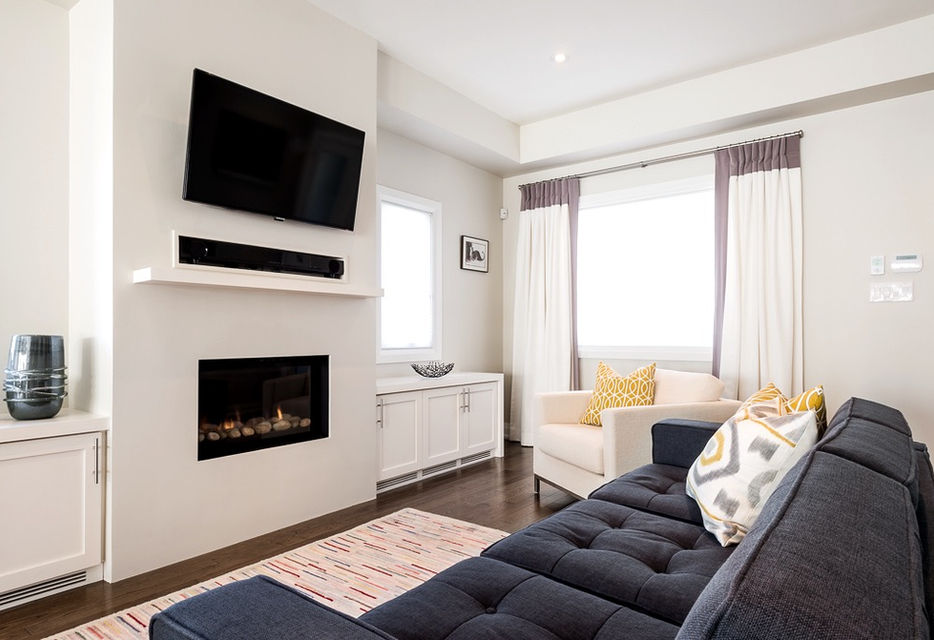 Modern living room with TV, fireplace, and couch; window and decorative pillows.