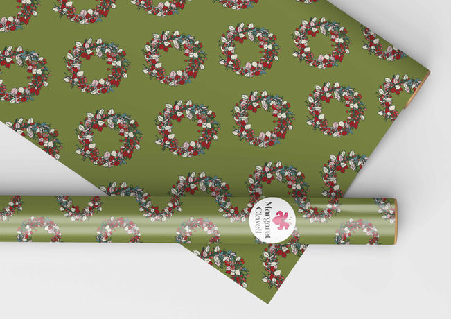 Floral and leaf wreath/garland in multiple colours on a green background shown on wrapping paper.