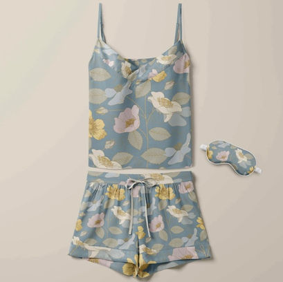 Set of silk pyjamas with a floral repeat pattern of field roses in pale colours of yellow, blue, pink, green and fawn on a mid denim blue background